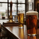Pint glazen met koperkleurige Britse bitter en een zachtere, blekere cask ale in een klassieke Engelse pub, met warme verlichting en brouwtraditie-atmosfeer.
