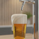 Gouden pils met dikke schuimkraag uit een home draft systeem in een modern thuistapsetting